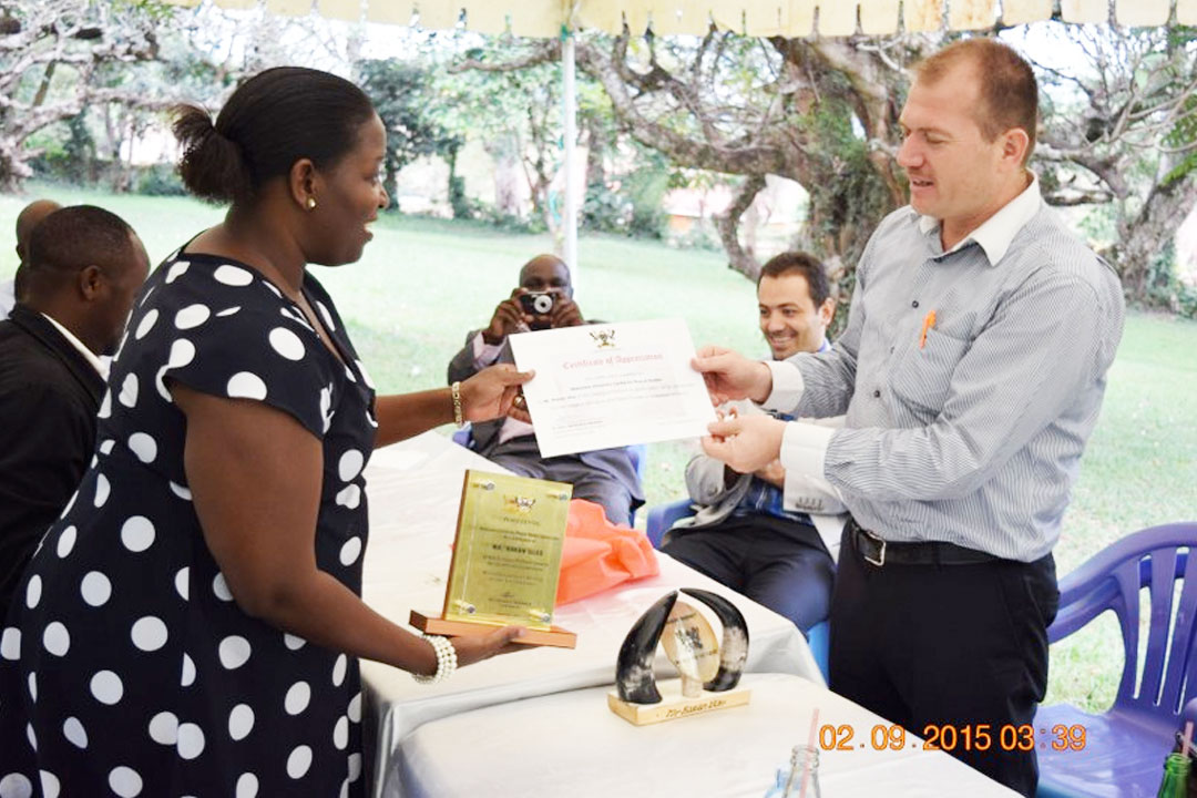Dr. Helen Nambalirwa presents Mr. Hakani with a certificate and plaque. (Photo Credit: Davies RWABU)